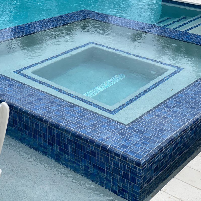 custom infinity edge spa with glass tile and waterfall edges